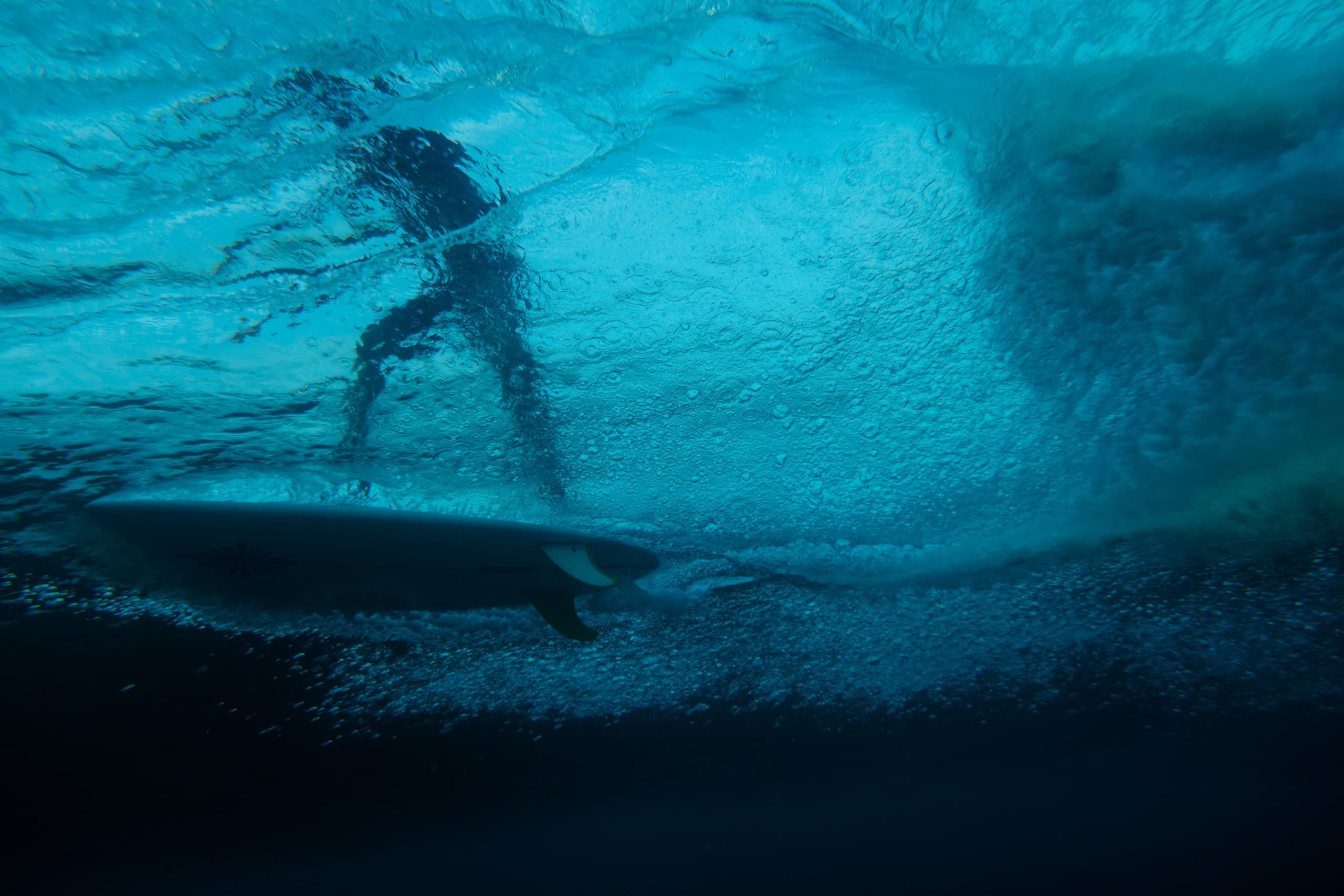 Surfer riding a wave, seen in silhouette from under the water